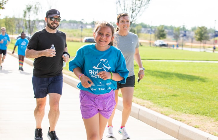 A Girls on the Run participant smiles next to a caregiver as they look down at a journal.